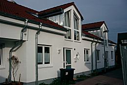 Modernes Reihenhaus mit roten Dächern.